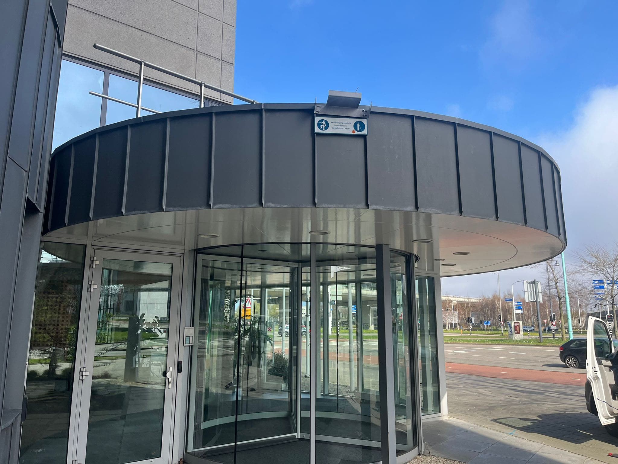 Ronde zinken overkapping boven de entree van een bedrijfspand