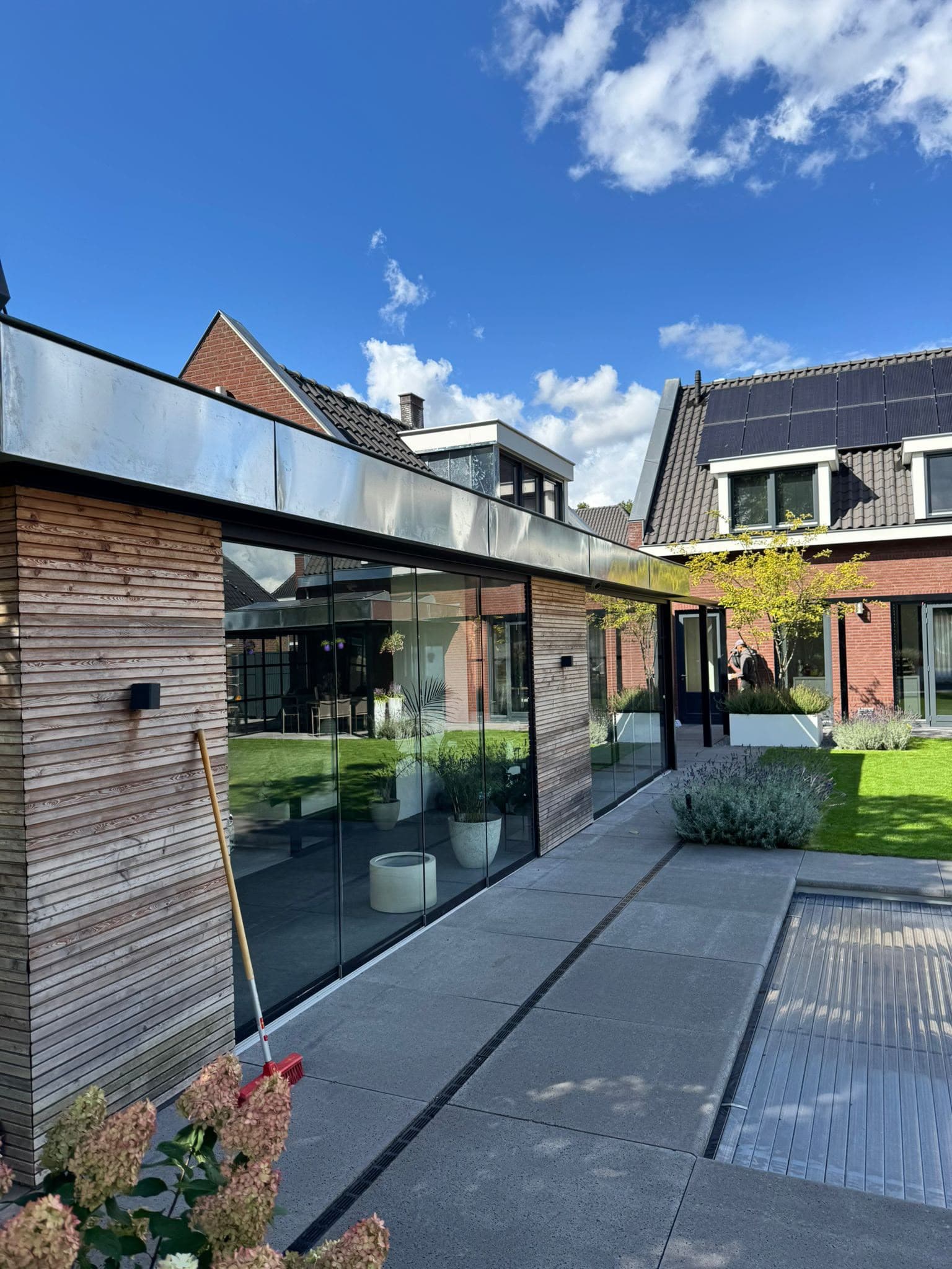 Moderne glazen aanbouw met een zinken dakrand langs het platte dak